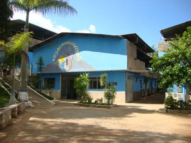 Foto real: fachada da Colônia Bom Samaritano, prédio azul com mural “Vidas Salvando Vidas”